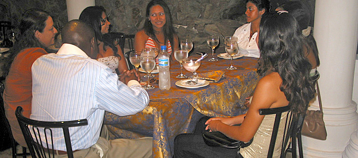 Dinner Conversation with Colombian Women and Black Man A group of Colombian women share stories and laughter with a Black man during a relaxed dinner in a warmly lit restaurant