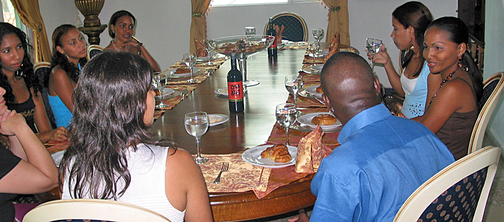 Black Man Dining with Colombian Women at Introduction Event A Black man surrounded by Colombian women smiling and enjoying conversation during a matchmaking dinner