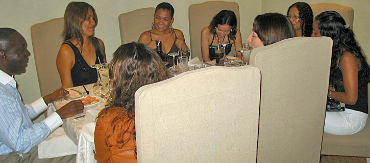 Friendly Dinner with Colombian Women and Black Man A Black man and Colombian women sit together around a restaurant table, smiling and talking during a matchmaking event