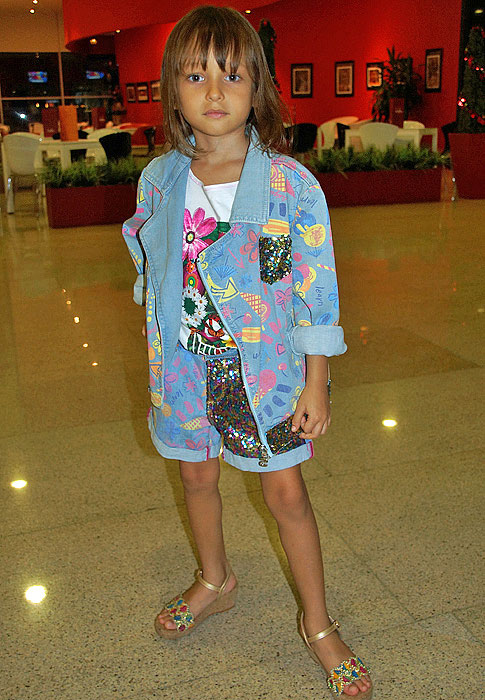 A future model on top of the fashion world with her colorful sandals and jean jacket and shorts splashed with colors