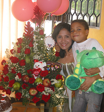 A Colombian woman receiving beautiful flowers, fruits, chocolate, cake, ballons, teddy bear and wine as a gift