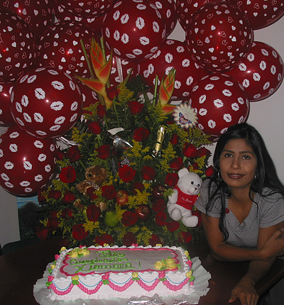A Colombian woman receiving beautiful flowers, fruits, chocolate, cake, ballons, teddy bear and wine as a gift