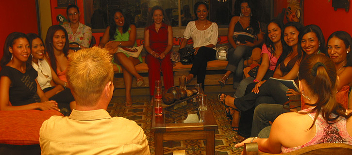 A group of Colombian women in a living room meeting a very happy man