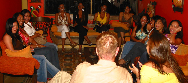 A group of Colombian women in a living room meeting a very happy man