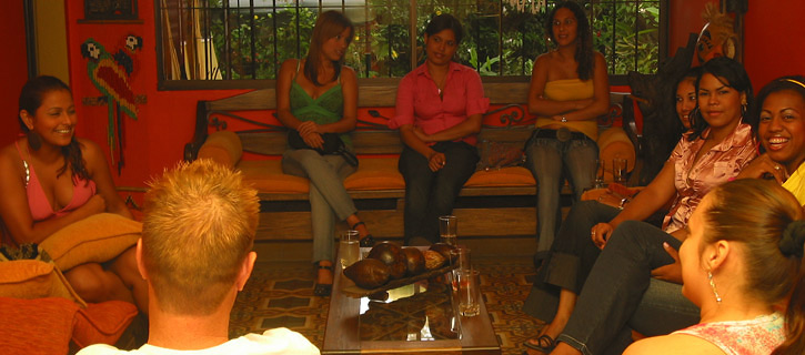 A group of Colombian women in a living room meeting a very happy man