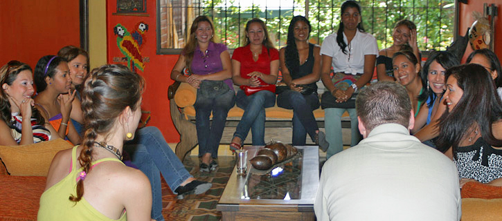 Colombian Women Group Introduction A group of Colombian women sitting in a semicircle talking with a visiting man during a friendly introduction meeting in a Latin-style living room