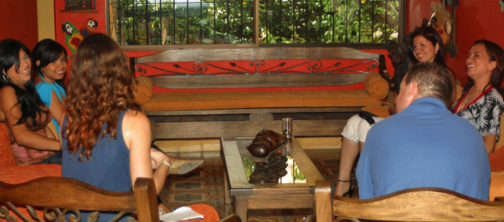 Informal Meeting with Colombian Women American man and several Colombian women seated in an orange-walled room, laughing and chatting during a relaxed matchmaking session