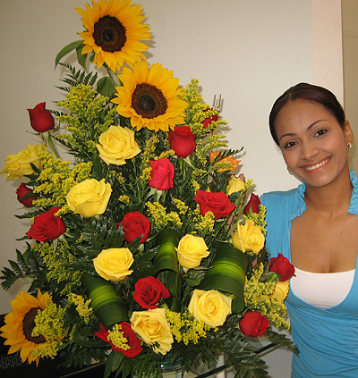 A Colombian woman receiving beautiful flowers, fruits, chocolate, teddy bear and wine as a gift