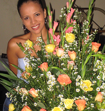 A Colombian woman receiving beautiful flowers, fruits, chocolate, teddy bear and wine as a gift