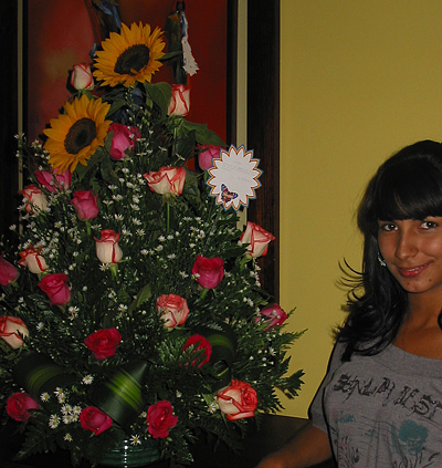 A Colombian woman receiving beautiful flowers, fruits, chocolate, teddy bear and wine as a gift