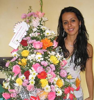 A Colombian woman receiving beautiful flowers, fruits, chocolate, teddy bear and wine as a gift