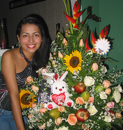 A Colombian woman receiving beautiful flowers, fruits, chocolate, teddy bear and wine as a gift