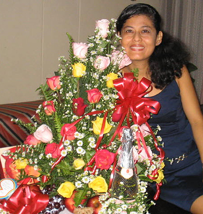 A Colombian woman receiving beautiful flowers, fruits, chocolate, teddy bear and wine as a gift