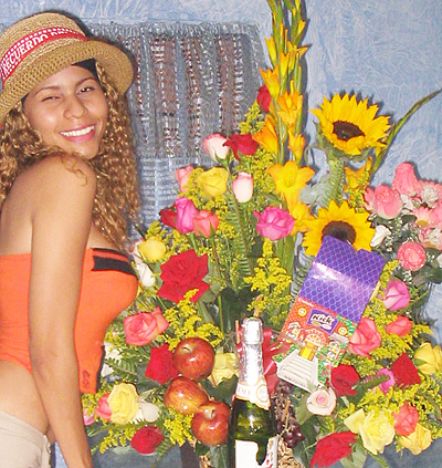 A Colombian woman receiving beautiful flowers, fruits, chocolate, teddy bear and wine as a gift