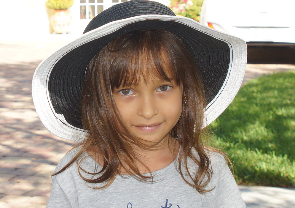 A six year old girl wearing a dark sun hat