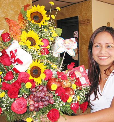 A Colombian woman receiving beautiful flowers, fruits, chocolate, teddy bear and wine as a gift