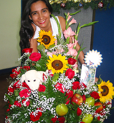 A Colombian woman receiving beautiful flowers, fruits, chocolate, teddy bear and wine as a gift