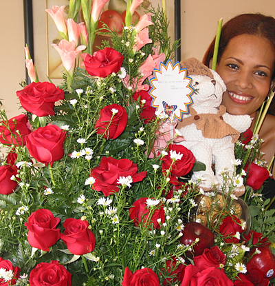 A Colombian woman receiving beautiful flowers, fruits, chocolate, teddy bear and wine as a gift