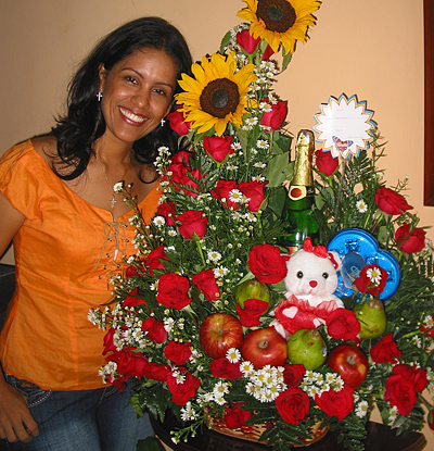 A Colombian woman receiving beautiful flowers, fruits, chocolate, teddy bear and wine as a gift