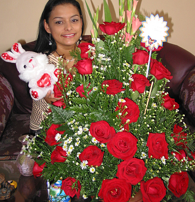 A Colombian woman receiving beautiful flowers, fruits, chocolate, teddy bear and wine as a gift