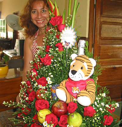 A Colombian woman receiving beautiful flowers, fruits, chocolate, teddy bear and wine as a gift