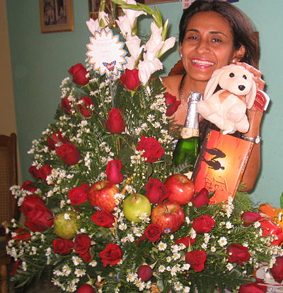 A Colombian woman receiving beautiful flowers, fruits, chocolate, teddy bear and wine as a gift