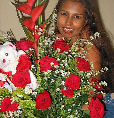 A Colombian woman receiving beautiful flowers, fruits, chocolate, teddy bear and wine as a gift