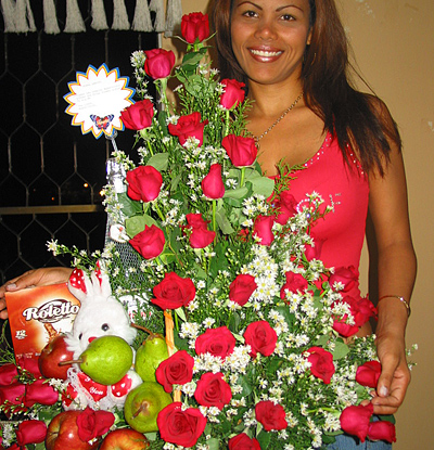 A Colombian woman receiving beautiful flowers, fruits, chocolate, teddy bear and wine as a gift