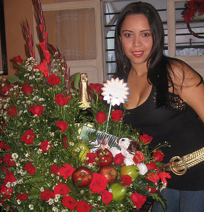 A Colombian woman receiving beautiful flowers, fruits, chocolate, teddy bear and wine as a gift