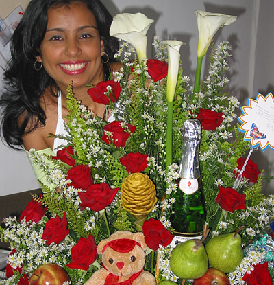 A Colombian woman receiving beautiful flowers, fruits, chocolate, teddy bear and wine as a gift