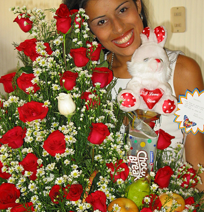 A Colombian woman receiving beautiful flowers, fruits, chocolate, teddy bear and wine as a gift