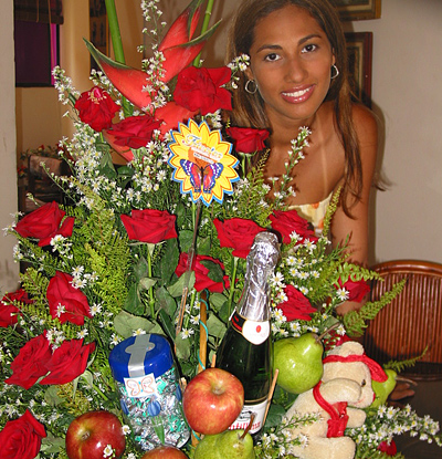 A Colombian woman receiving beautiful flowers, fruits, chocolate, teddy bear and wine as a gift