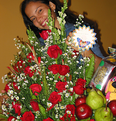 A Colombian woman receiving beautiful flowers, fruits, chocolate, teddy bear and wine as a gift