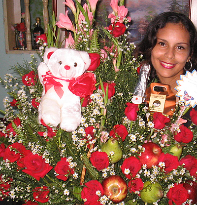 A Colombian woman receiving beautiful flowers, fruits, chocolate, teddy bear and wine as a gift