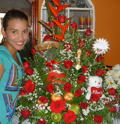 A Colombian woman receiving beautiful flowers, fruits, chocolate, teddy bear and wine as a gift