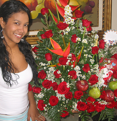 A Colombian woman receiving beautiful flowers, fruits, chocolate, teddy bear and wine as a gift