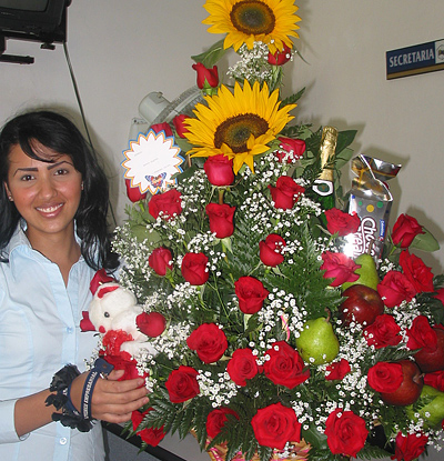 A Colombian woman receiving beautiful flowers, fruits, chocolate, teddy bear and wine as a gift