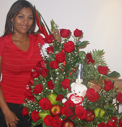 A Colombian woman receiving beautiful flowers, fruits, chocolate, teddy bear and wine as a gift