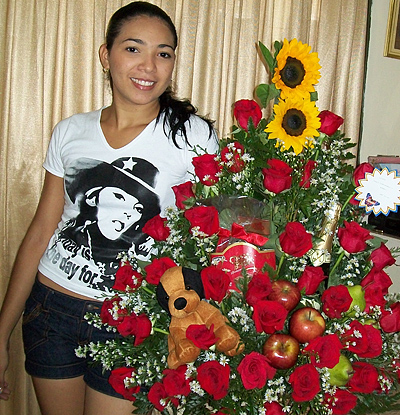 A Colombian woman receiving beautiful flowers, fruits, chocolate, teddy bear and wine as a gift