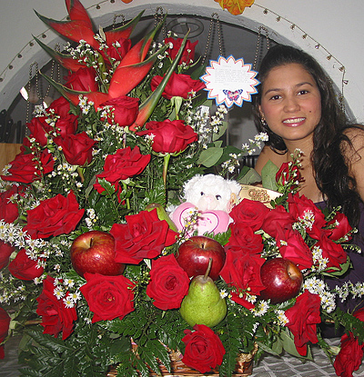 A Colombian woman receiving beautiful flowers, fruits, chocolate, teddy bear and wine as a gift