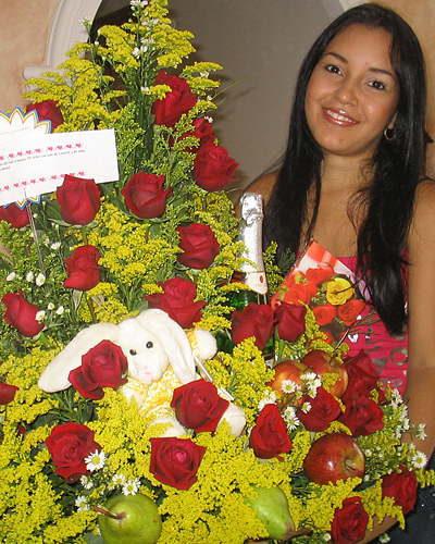 A Colombian woman receiving beautiful flowers, fruits, chocolate, teddy bear and wine as a gift