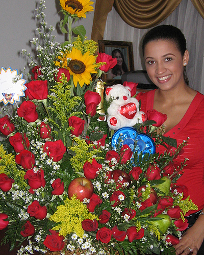 A Colombian woman receiving beautiful flowers, fruits, chocolate, teddy bear and wine as a gift