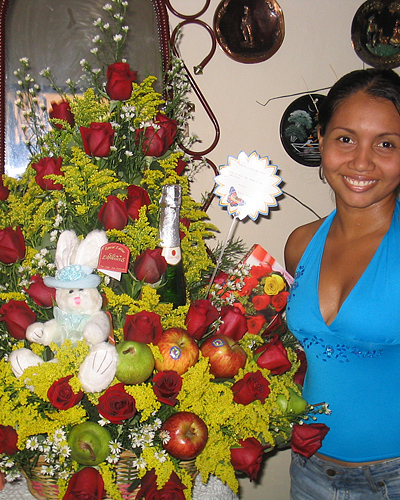 A Colombian woman receiving beautiful flowers, fruits, chocolate, teddy bear and wine as a gift