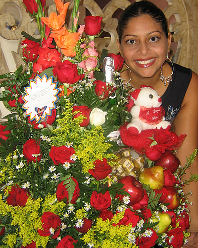 A Colombian woman receiving beautiful flowers, fruits, chocolate, teddy bear and wine as a gift