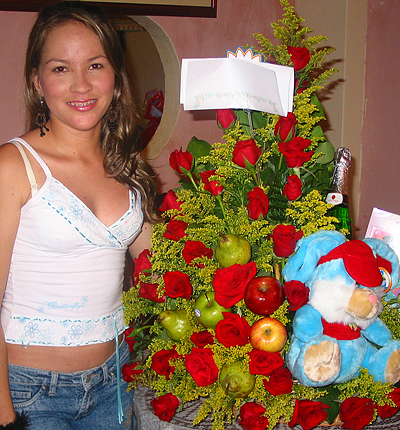 A Colombian woman receiving beautiful flowers, fruits, chocolate, teddy bear and wine as a gift