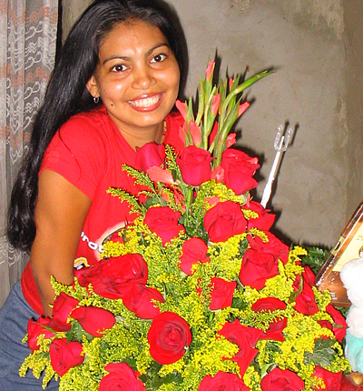 A Colombian woman receiving beautiful flowers, fruits, chocolate, teddy bear and wine as a gift