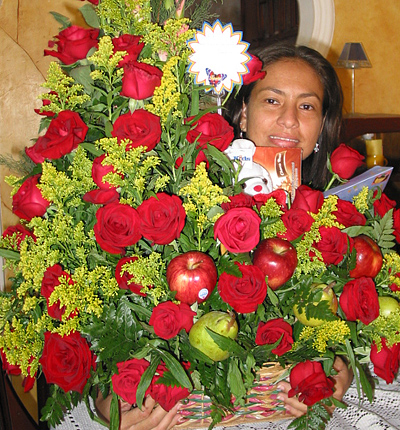 A Colombian woman receiving beautiful flowers, fruits, chocolate, teddy bear and wine as a gift