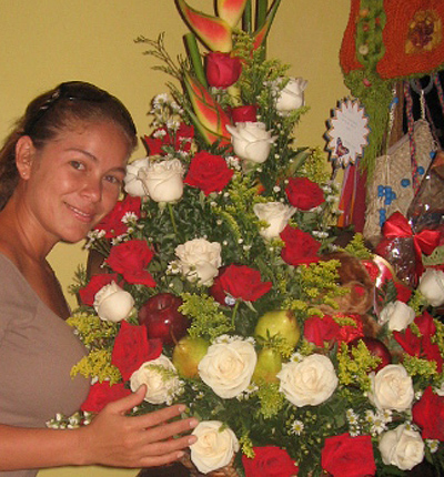 A Colombian woman receiving beautiful flowers, fruits, chocolate, teddy bear and wine as a gift