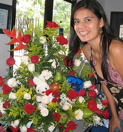 A Colombian woman receiving beautiful flowers, fruits, chocolate, teddy bear and wine as a gift