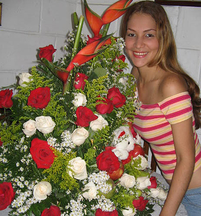 A Colombian woman receiving beautiful flowers, fruits, chocolate, teddy bear and wine as a gift